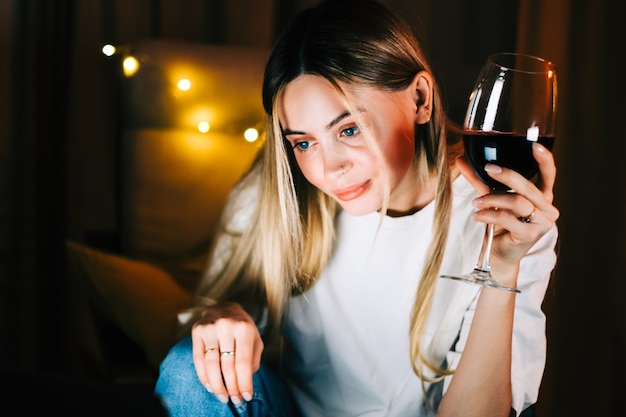 Young millennial woman having video call on laptop computer and drinking wine, use technology for communicate with friends or family.