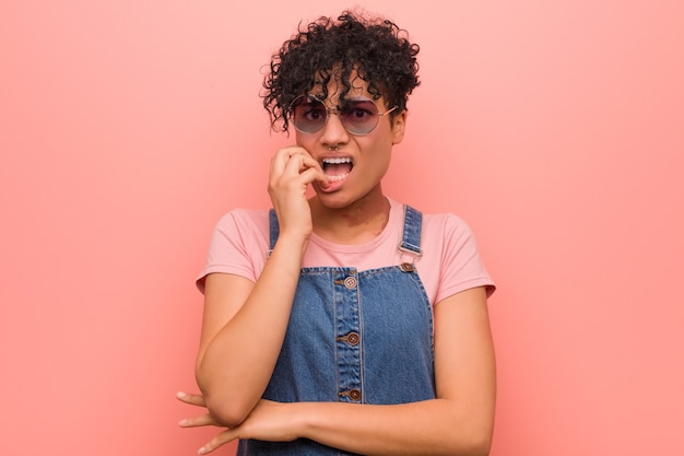 Young mixed african american teenager woman biting fingernails, nervous and very anxious.