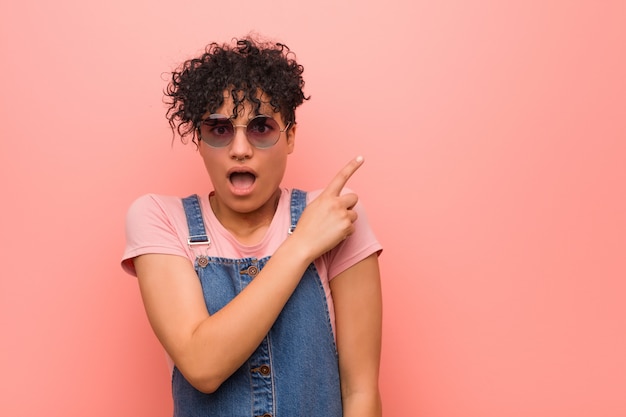 Young mixed african american teenager woman pointing to the side