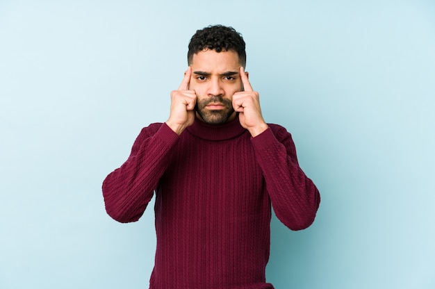 Young mixed race arabic man isolated focused on a task, keeping forefingers pointing head.