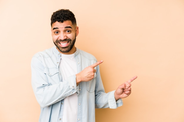 Young mixed race arabic man isolated shocked pointing with index fingers to a copy space.