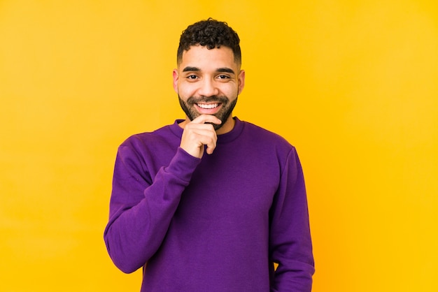 Young mixed race arabic man isolated smiling happy and confident, touching chin with hand.