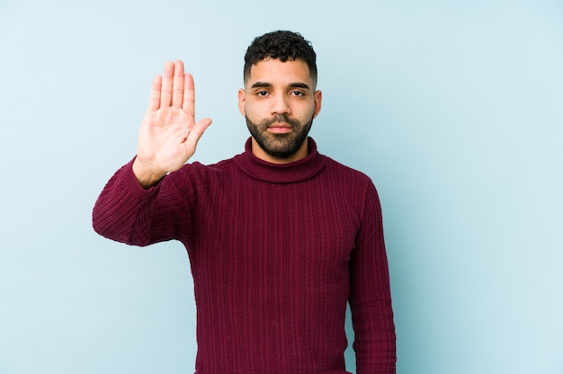 Young mixed race arabic man isolated standing with outstretched hand showing stop sign, preventing you.