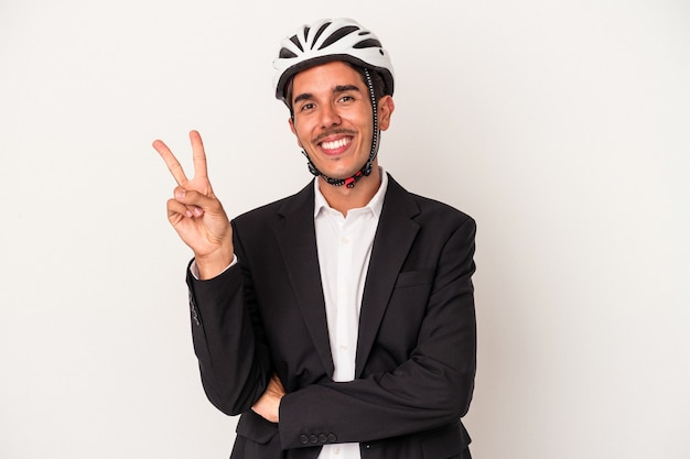 Young mixed race business man wearing a bike helmet isolated on white background joyful and carefree showing a peace symbol with fingers.