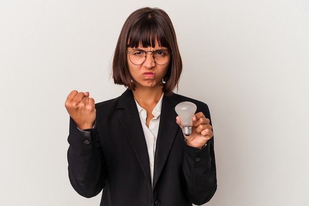 Young mixed race business woman holding a light bulb isolated on white background showing fist to camera, aggressive facial expression.