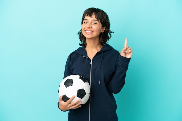 Young mixed race football player woman isolated on blue background showing and lifting a finger in sign of the best