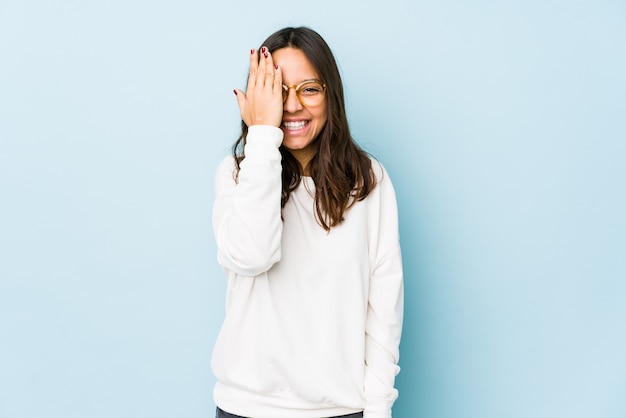 Young mixed race hispanic woman isolated having fun covering half of face with palm.