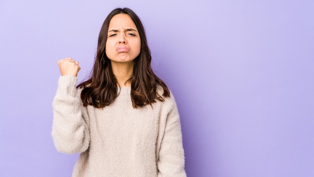 Young mixed race hispanic woman isolated showing fist, aggressive facial expression.