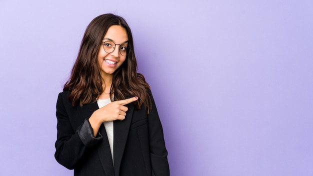 Young mixed race hispanic woman isolated smiling and pointing aside, showing something at blank space.