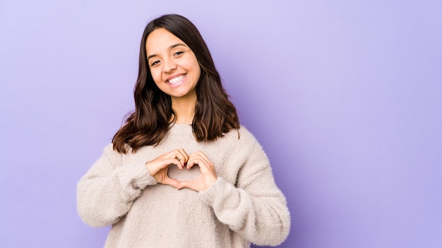 Young mixed race hispanic woman isolated smiling and showing a heart shape with hands.