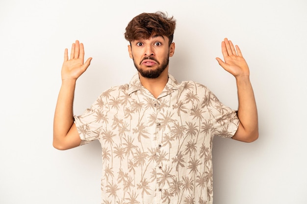 Young mixed race man isolated on grey background being shocked due to an imminent danger