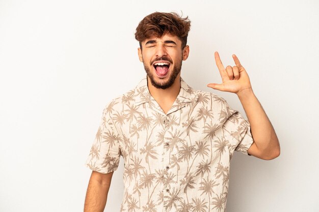 Young mixed race man isolated on grey background showing rock gesture with fingers