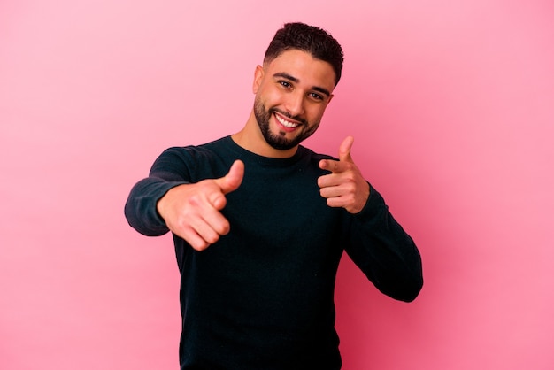 Young mixed race man isolated on pink background cheerful smiles pointing to front.