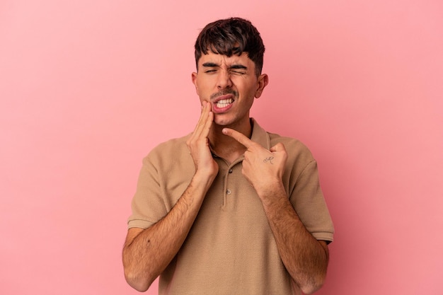 Young mixed race man isolated on pink background having a strong teeth pain, molar ache.