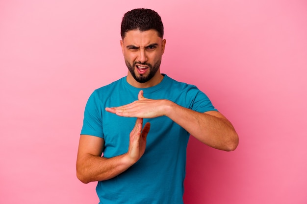 Young mixed race man isolated on pink background showing a timeout gesture.