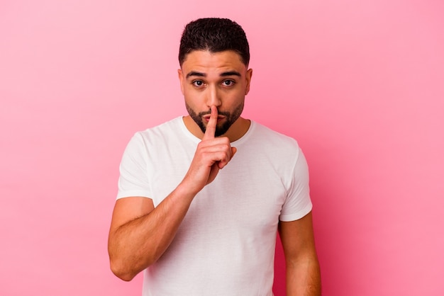 Photo young mixed race man isolated on pink keeping a secret or asking for silence.