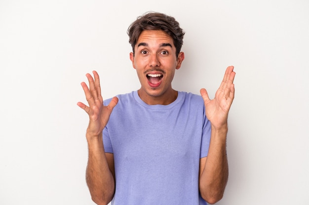 Young mixed race man isolated on white background celebrating a victory or success, he is surprised and shocked.