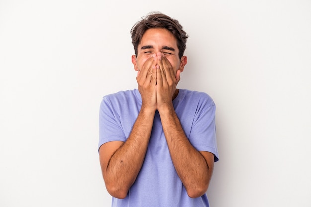 Young mixed race man isolated on white background laughing about something, covering mouth with hands.