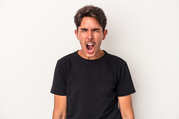 Young mixed race man isolated on white background shouting very angry, rage concept, frustrated.