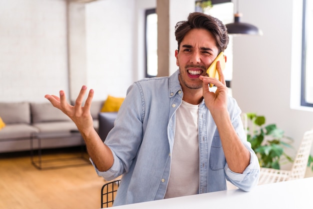 Young mixed race man talking on the phone in a kitchen