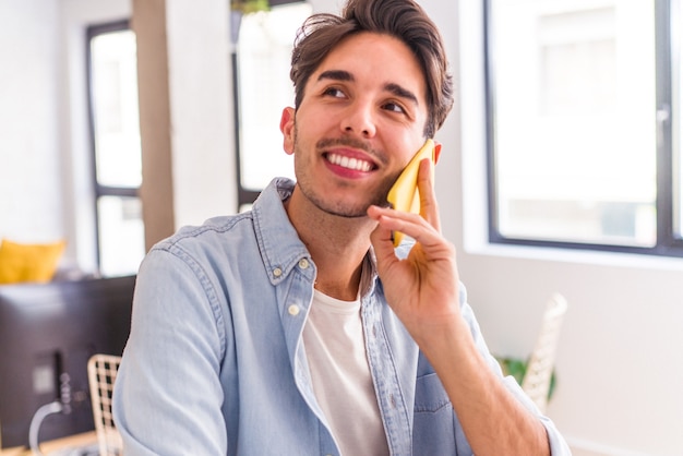 Young mixed race man talking on the phone in a kitchen