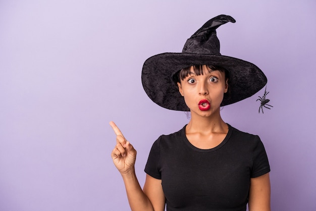 Photo young mixed race woman disguised as a witch isolated on purple background  pointing to the side