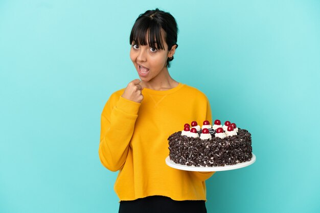 Young mixed race woman holding birthday cake celebrating a victory