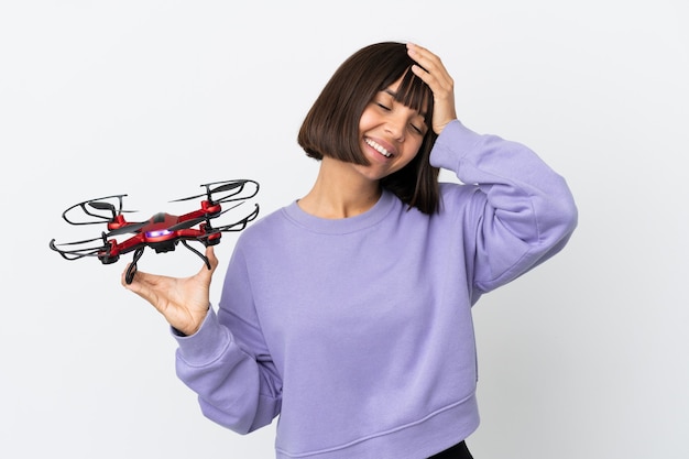 Young mixed race woman holding a drone isolated on white background smiling a lot