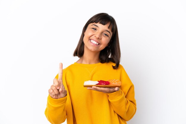 Young mixed race woman holding sashimi isolated on white background showing and lifting a finger