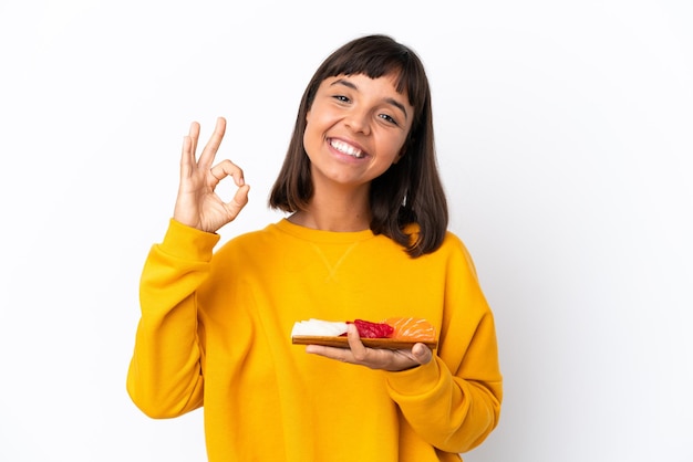 Young mixed race woman holding sashimi isolated on white background showing ok sign with fingers