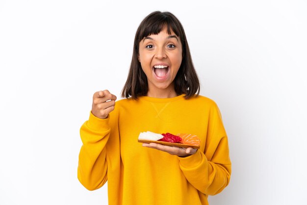 Young mixed race woman holding sashimi isolated on white background surprised and pointing front