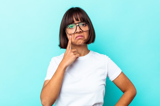 Young mixed race woman isolated on blue background crying, unhappy with something, agony and confusion concept.