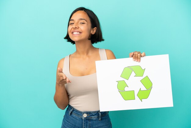 Young mixed race woman isolated holding a placard with recycle icon making a deal