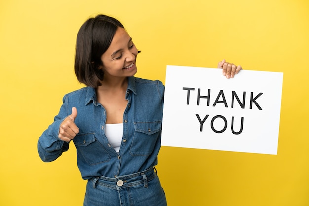 Young mixed race woman isolated holding a placard with text THANK YOU with thumb up