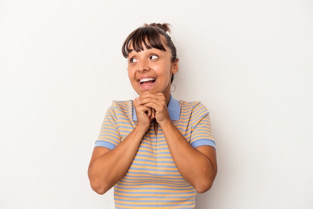 Young mixed race woman isolated on white background  keeps hands under chin, is looking happily aside.