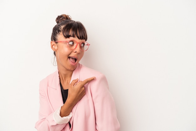 Young mixed race woman isolated on white background  points with thumb finger away, laughing and carefree.