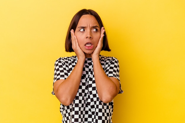 Young mixed race woman isolated on yellow background scared and afraid.