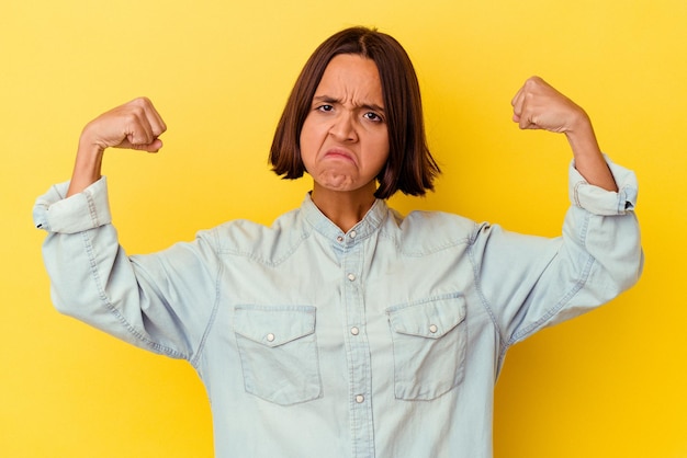 Photo young mixed race woman isolated on yellow background showing strength gesture with arms, symbol of feminine power