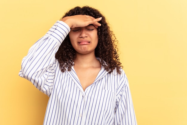 Young mixed race woman isolated on yellow background touching temples and having headache.