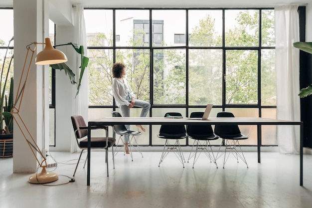 Young mixed race woman relaxing looking out the window in a bright spacious living room Copy space