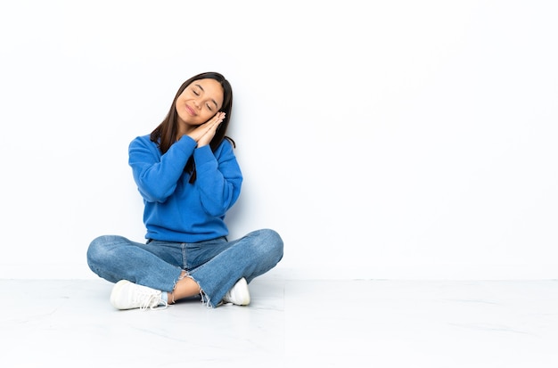 Young mixed race woman sitting on the floor isolated