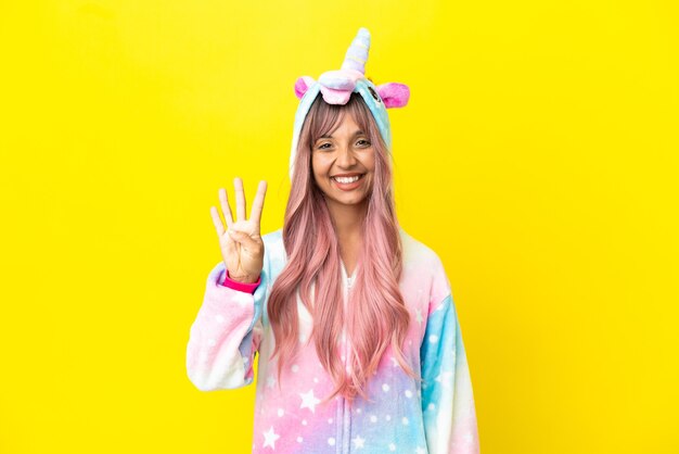 Young mixed race woman wearing a unicorn pajama isolated on white background happy and counting four with fingers