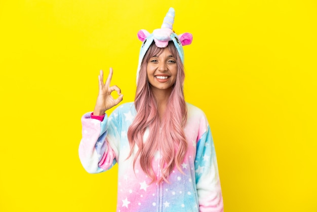 Young mixed race woman wearing a unicorn pajama isolated on white background showing ok sign with fingers