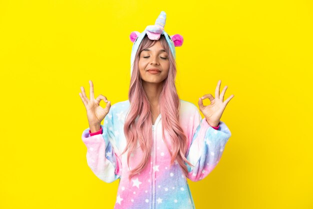 Young mixed race woman wearing a unicorn pajama isolated on white background in zen pose