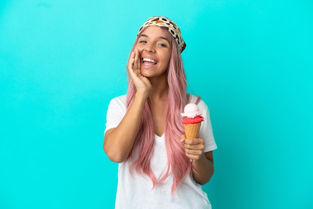 Young mixed race woman with a cornet ice cream isolated on blue background shouting with mouth wide open