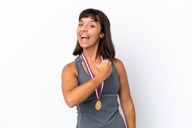 Young mixed race woman with medals isolated on white background celebrating a victory