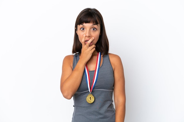 Young mixed race woman with medals isolated on white background surprised and shocked while looking right