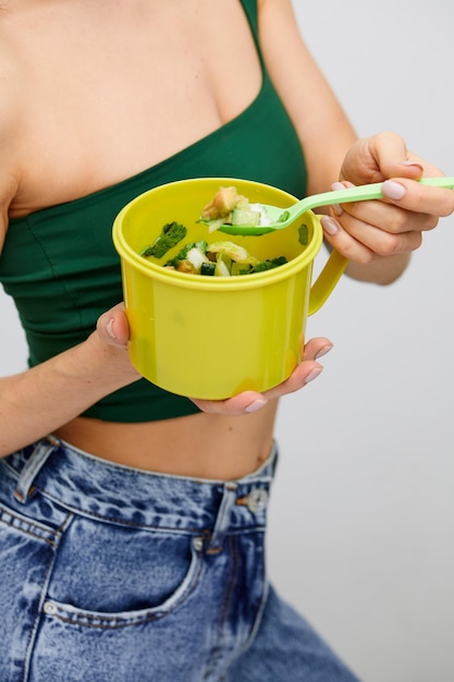 Young model healthy woman eating green vegetables avocado cucumber and green herbs Detoxification vegetarian healthy eating and diet concept