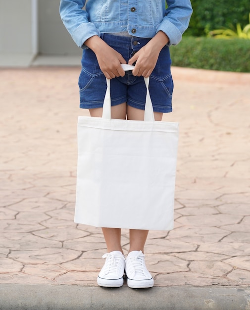 Young model holding white tote bag for mockup blank template