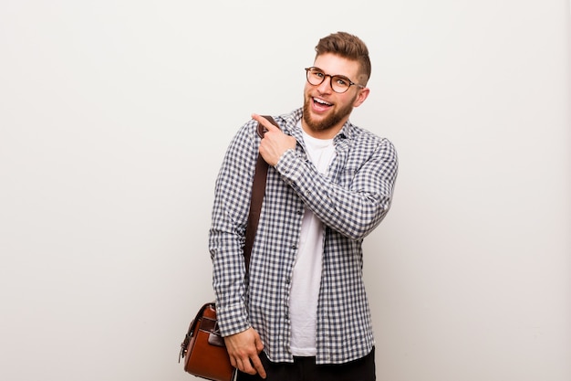 Young modern business man smiling and pointing aside, showing something at blank space.